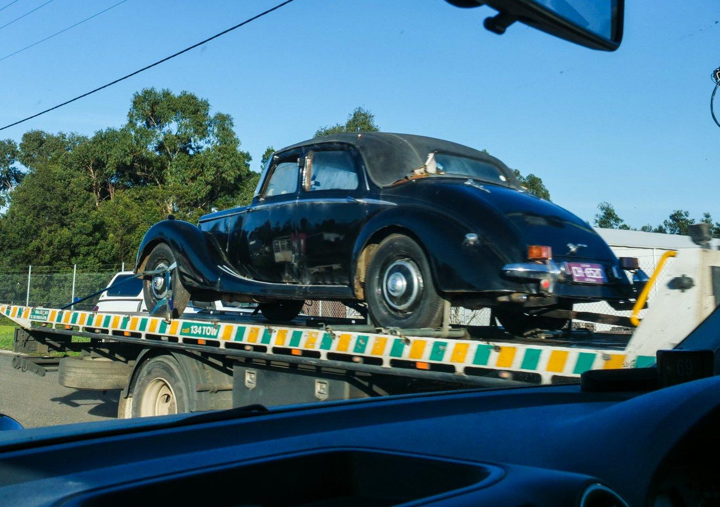 Old car, maybe a Rlley, being towed.
